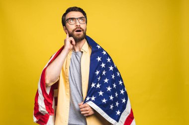 Sarı arka planda izole edilmiş Amerikan bayrağı taşıyan sakallı mutlu bir adamın portresi..