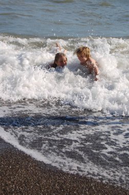 Çocuklar çocuklar kardeşler yazın dalgalarda birlikte yüzüyorlar.