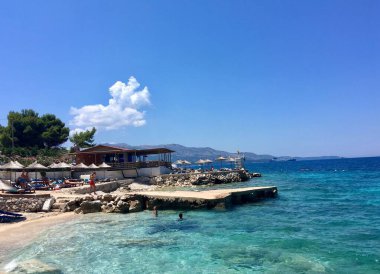 Arnavutluk 'un Ksamil kentinde güneşli bir günde plajlı deniz manzarası 