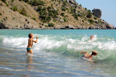 Çocuklar erkek kardeşler yaz tatilinde deniz dalgalarında birlikte oynuyorlar. 