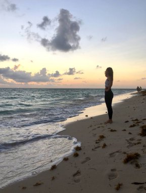 Okyanus üzerinde gün doğumuyla birlikte manzara ve Dominik Cumhuriyeti sahilinde genç bir kadının silueti. 