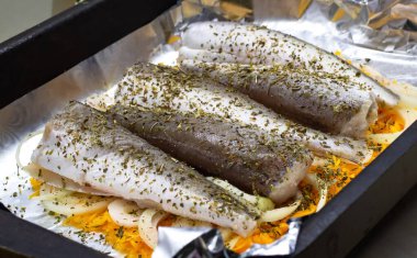 Baharatlı ve folyolu beş çiğ balık, pişirmeye hazır. Hake yemek için hazır. Ev yapımı yemek. keto diyeti 