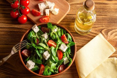 Ahşap bir tahtanın üzerindeki seramik bir kasede mung fasulyesi salatası, peynir, kiraz. (Valerianella Locusta) Diyet ve sağlıklı gıda konsepti. Fogerlsalat. keto diyeti 