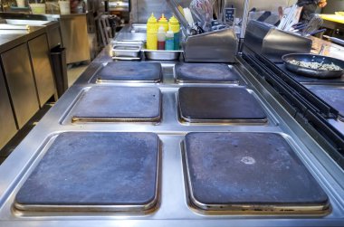 Mutfak aletleri de dahil olmak üzere modern bir restoranın büyük profesyonel mutfağının elektrikli ocağının bir parçası. Profesyonel mutfak malzemeleri. Isıtma yüzeyi