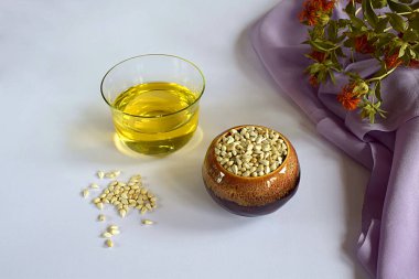 Safra çiçeği. Safran yağı, kabın içindeki tohumlar ve beyaz bir yüzeye yayılmış çiçekler..