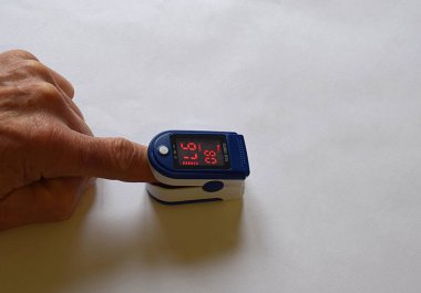Çalışan bir oksimetre cihazındaki parmağın yakın plan görüntüsü
