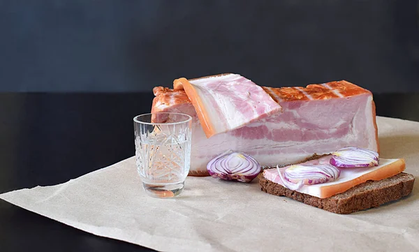 Göğüs eti, göğüs eti ve soğanlı sandviç ve kağıt üzerinde bir bardak votka..