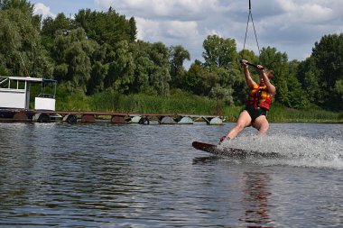 Genç bir kadın nehirde wakeboard sürmeyi öğreniyor..