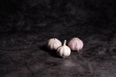 Sarımsak grubunun gösterişsiz görüntüsü. Gri taş masa arka planı. Uzay resmini kopyala. Soğuk algınlığı ve enfeksiyonları önlemek için antiseptik özellikleri olan iyi bir ilaç. Sağlıklı beslenme.