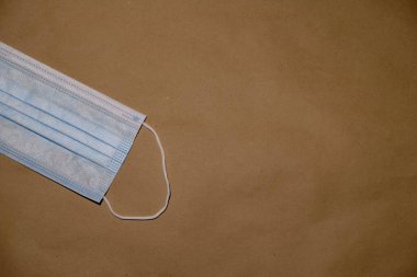 Arka plan olarak kahverengi kağıttaki koruyucu yüz maskesi. Alerjinin korunması, koronavirüs, grip ve diğer hastalıklar ve virüs enfeksiyonları. Boşluk resmini kopyala.