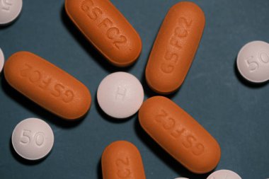 Tidewater yeşil renkli arka planda HIV tedavisi için beyaz ve turuncu antiretroviral tedavi hapları. Dolutegravir, Abacavir, Lamivudine. Dünya AIDS Günü konsepti. Sağlık ve İlaç Hizmetleri.