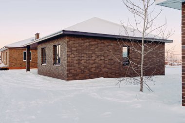 Karlı bir kış akşamının arka planında bir katlı tuğla ev. Daha fazla satış için düşük katlı binaların inşaatı. İnşaat işi kavramı.