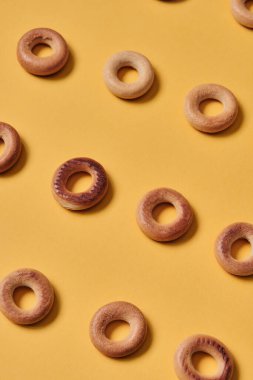 Sarı yüzeydeki Sushki deseninin üst görüntüsü. Rus ve Ukrayna mutfağından yemekler, hamur şeklinde katı halka şeklinde ürünler, koyun eti ürünleri. Slavlar arasında en yaygın çay atıştırmalıklarından biri.