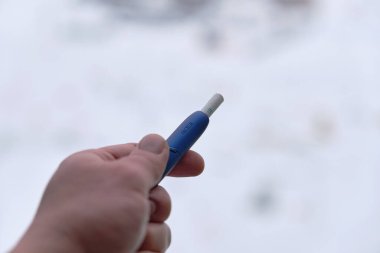 Kazan, Tataristan, Rusya - 29 Aralık 2020: IQOS elektronik sigarası ve erkek eli değneği. Boşluk resmini kopyala.