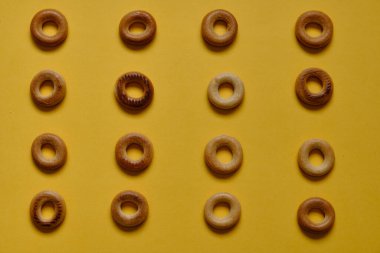 Sarı yüzeydeki Sushki deseninin üst görüntüsü. Rus ve Ukrayna mutfağından yemekler, hamur şeklinde katı halka şeklinde ürünler, koyun eti ürünleri. Slavlar arasında en yaygın çay atıştırmalıklarından biri.