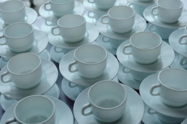 Kahve ve çay için bir grup boş beyaz fincan ve sosis, kahvaltı ya da büfede yemek servisi yapmak için masada sırada bekliyorlar. Seçici odak 