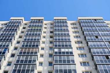Facade of typical modern multi-storey building and vibrant blue sky as background. Residential complex called Green. Copy space image.