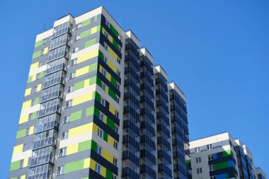 Facade of typical modern multi-storey building and vibrant blue sky as background. Residential complex called Green. Copy space image.