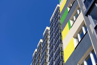 Facade of typical modern multi-storey building and vibrant blue sky as background. Residential complex called Green. Copy space image.