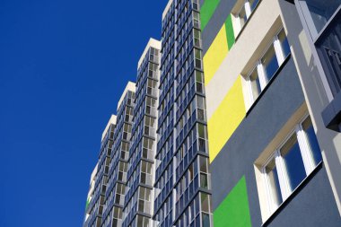 Facade of typical modern multi-storey building and vibrant blue sky as background. Residential complex called Green. Copy space image.
