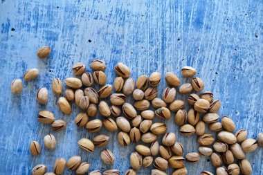 Arka plan olarak bulanık boyanmış taş masadaki tuzlu ve kurutulmuş Pistachios 'un üst görüntüsü. Sağlıklı beslenme kavramı. Seçici odaklanma. Boşluğu kopyala.