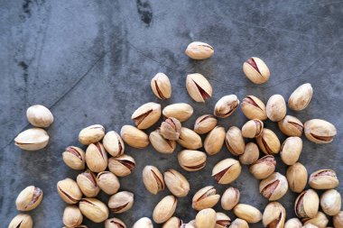 Arka plan olarak bulanık boyanmış taş masadaki tuzlu ve kurutulmuş Pistachios 'un üst görüntüsü. Sağlıklı beslenme kavramı. Seçici odaklanma. Boşluğu kopyala.
