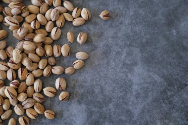 Arka plan olarak bulanık boyanmış taş masadaki tuzlu ve kurutulmuş Pistachios 'un üst görüntüsü. Sağlıklı beslenme kavramı. Seçici odaklanma. Boşluğu kopyala.