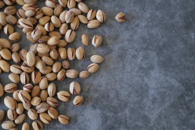Arka plan olarak bulanık boyanmış taş masadaki tuzlu ve kurutulmuş Pistachios 'un üst görüntüsü. Sağlıklı beslenme kavramı. Seçici odaklanma. Boşluğu kopyala.