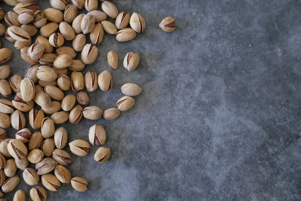 Arka plan olarak bulanık boyanmış taş masadaki tuzlu ve kurutulmuş Pistachios 'un üst görüntüsü. Sağlıklı beslenme kavramı. Seçici odaklanma. Boşluğu kopyala.