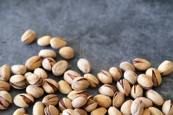 Arka plan olarak bulanık boyanmış taş masadaki tuzlu ve kurutulmuş Pistachios 'un üst görüntüsü. Sağlıklı beslenme kavramı. Seçici odaklanma. Boşluğu kopyala.
