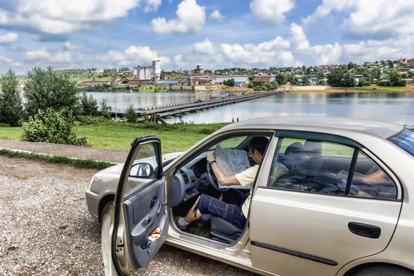 Auto viaggiatore studia una mappa sullo sfondo della città Birsk . — Foto Stock