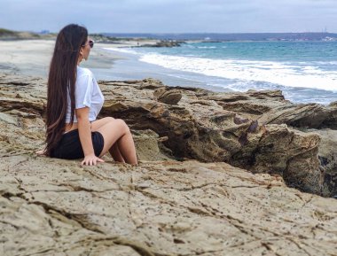 Kumsalın önünde oturan kadın.