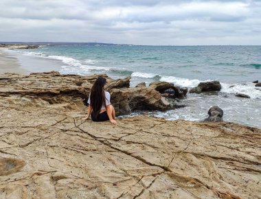 Kumsalın önünde oturan kadın.