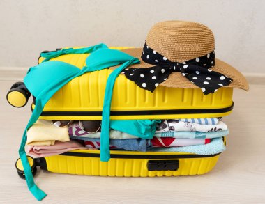 Zeminde sarı bir valizle dolaşmak için giysi ve aksesuarlar.