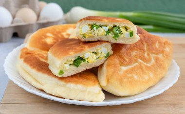 Beyaz tabakta yeşil soğan ve yumurta ile doldurulmuş tortilla hamuru. Kızarmış turtalar yakın plan..