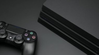 Chengdu, Çin. 26 Kasım 2019. Sony Play Station 4 Pro oyun konsolu yanında kumanda kolu olan siyah masada izole edildi. Darksiders 3 video oyunu ile CD 'yi çıkart.