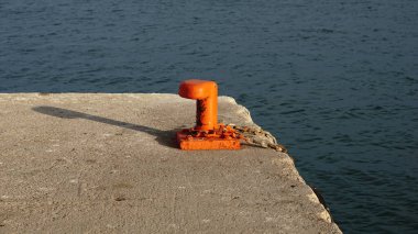 Paslı kırmızı kazık, deniz kenarına demirlemiş.