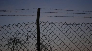 Alacakaranlıkta dikenli tellerle çit