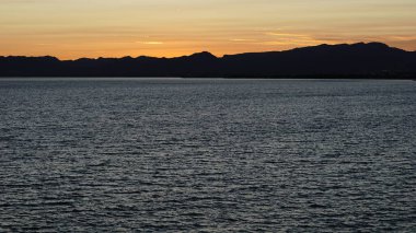 Gün batımı dağların üzerinde ve denizin üzerinde