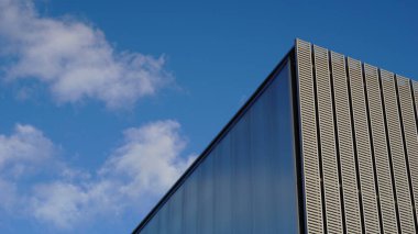 Bulutlu gökyüzüne karşı bir ofis binasının çatısı ve cephesi