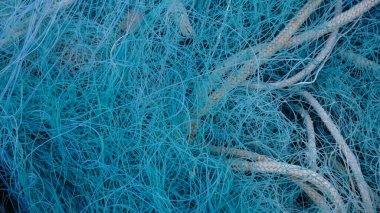 Kalın örgülü iplerle birbirine dolanmış yoğun mavi balıkçı ağı aşınma, aşınma ve katmanlı endüstriyel lifler gösteriyor.