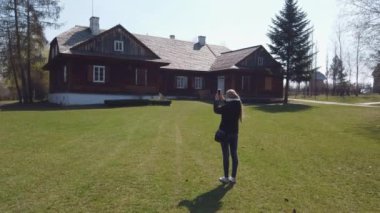 Kız turist, eski bir Avrupa köyündeki ahşap evin fotoğraflarını çekiyor.