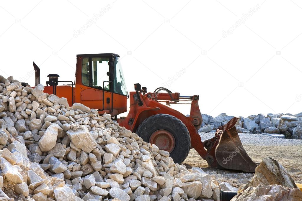 A digger builds a dam of white stones