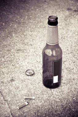 Şişe bira'nın üç sigara izmaritleri ile yere dinlenme