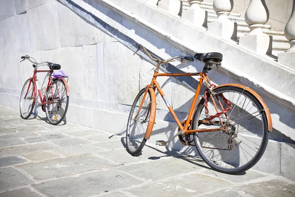 Två gamla rostiga cyklar mot en marmor vägg (Toscana - Italien) — Stockfoto