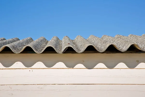 Old aged dangerous roof made of corrugated asbestos panels - one of the most dangerous materials in buildings and construction industry so-called hidden killer.