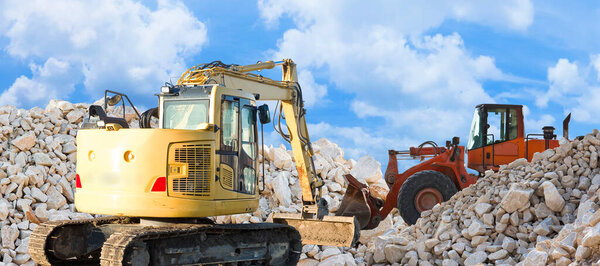 Diggers building a dam of white stones on a construction site.