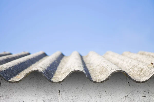 白い石の壁に対する危険なアスベストスの屋根 建設業界で最も危険な材料の1つ — ストック写真
