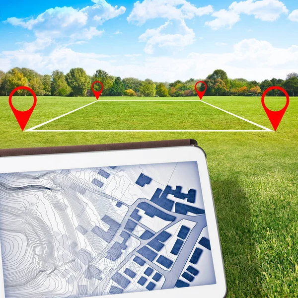 Land plot management - real estate concept with a vacant land on a green field available for building construction and housing subdivision in a residential area for sale - Digital tablet on foreground with an imaginary cadastral map