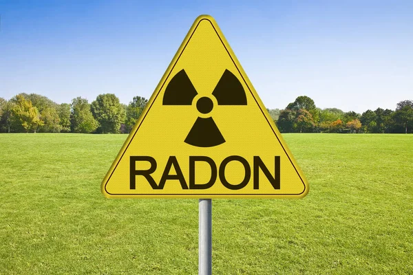 Danger of radioactive contamination from RADON GAS - concept with warning symbol of radioactivity on road sign against a building lot and vacant land available for building construction.